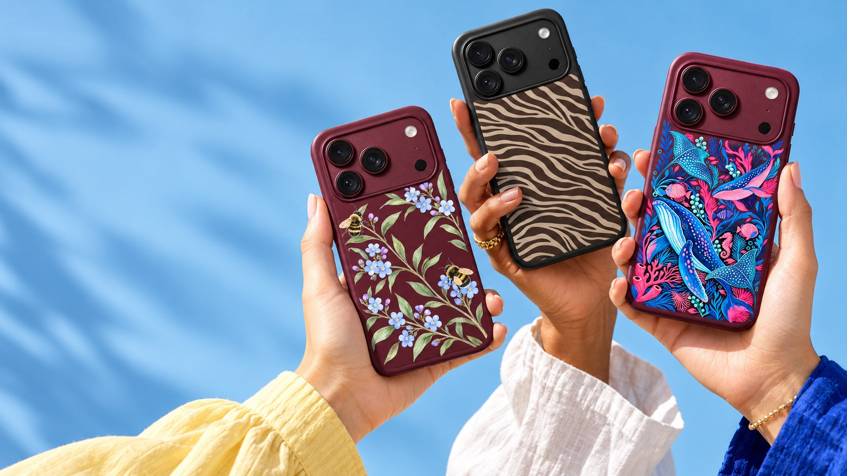 Three hands holding Marblefy floral, cocoa zebra and ocean-print cases